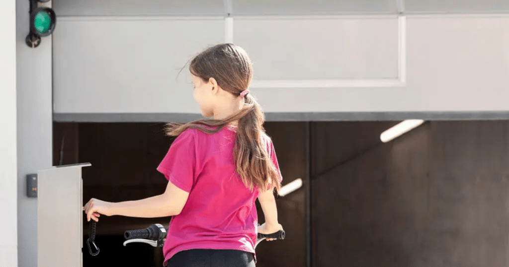 a girl riding a bike touching the garage door sensor